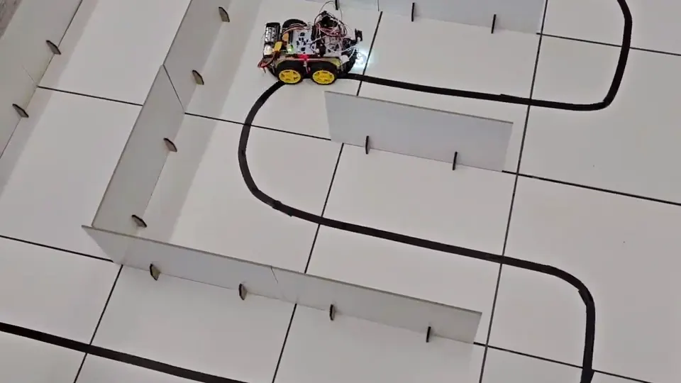 A small four-wheel robot on a white board, following a black line around a tight bend.