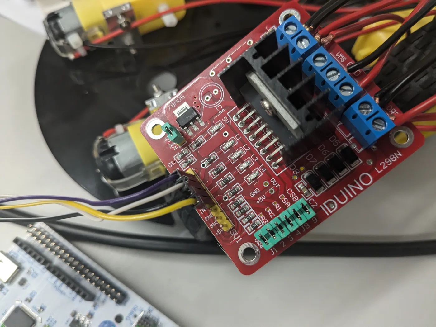 Close-up of the red motor driver board with blue screw terminals and the motor leads attached.